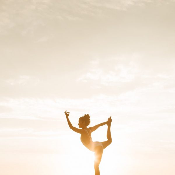 woman yoga pose sun behind